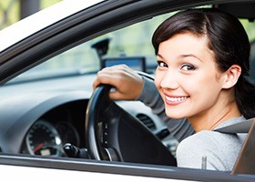 Woman smiling at the wheel because she has the cheapest car insurance in Massapequa